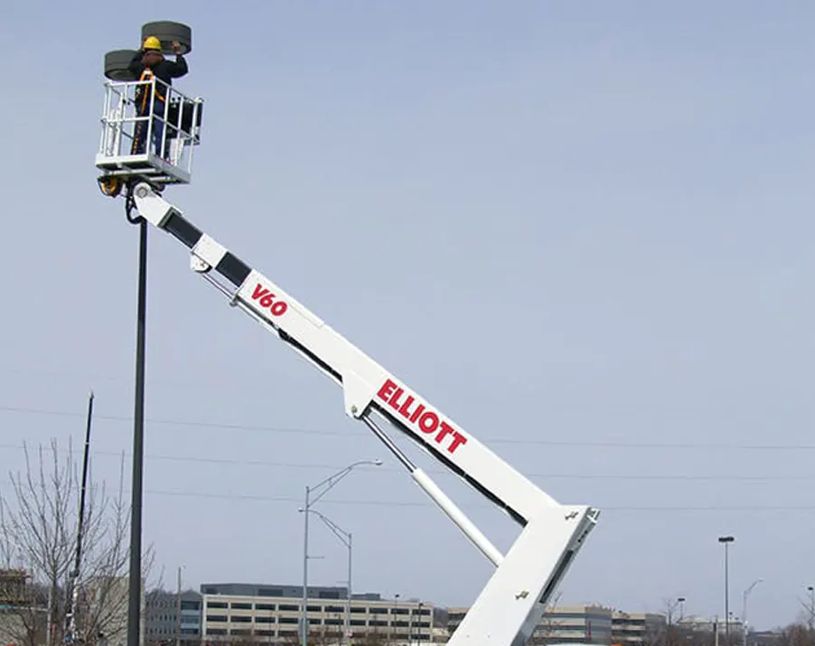Technician in a lift working on a fixture at the top of a parking lot light pole
