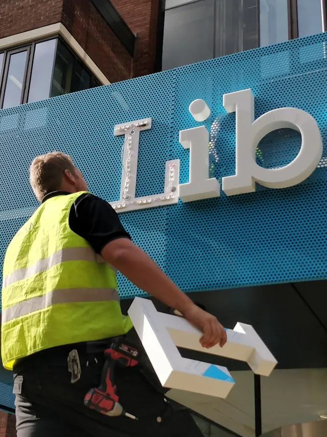 Technician installing a commercial building sign