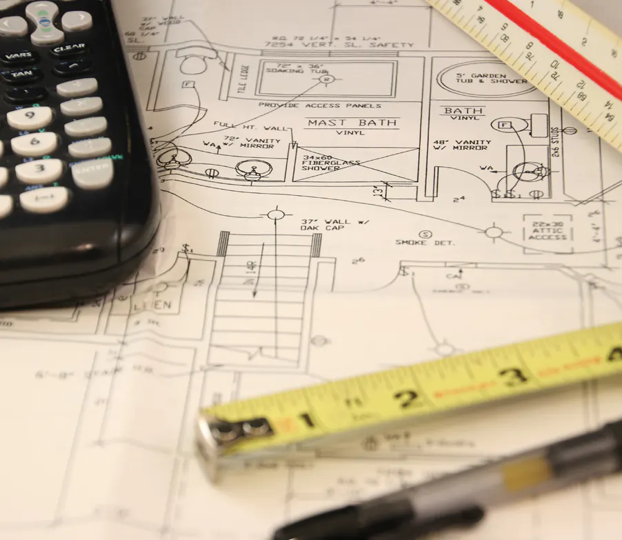Scaled drawings with a tape measure and calculator on a work surface