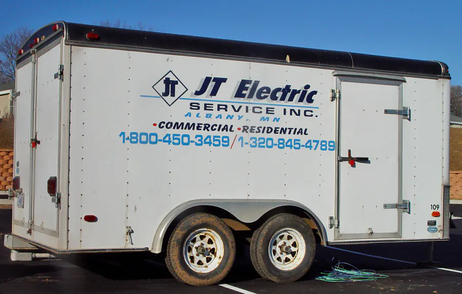 Logo and contact numbers lettered on the side of an enclosed trailer